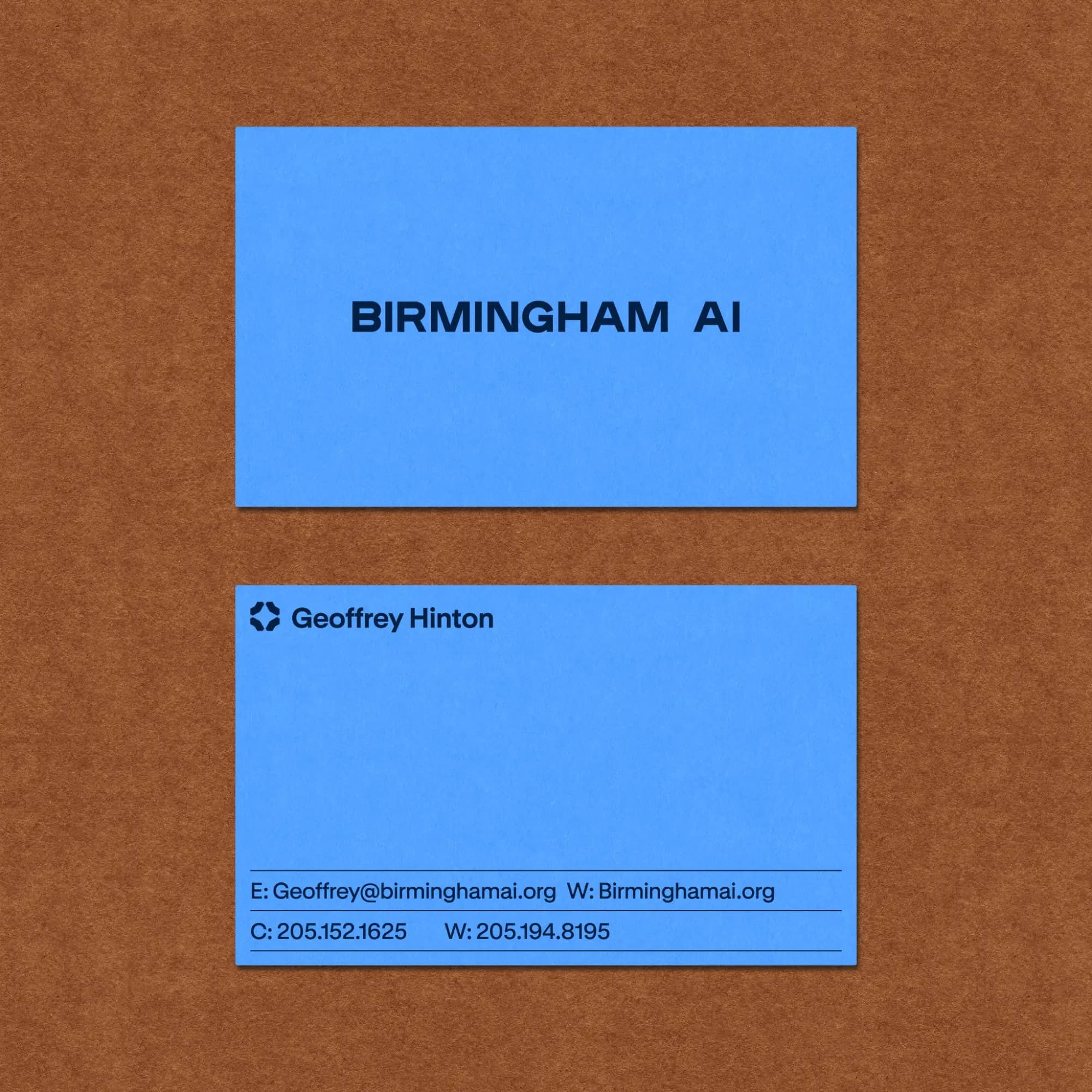 Two blue Birmingham AI business cards on brown paper: BIRMINGHAM AI across the front, and the mark, name, email, site and phone lines on the back