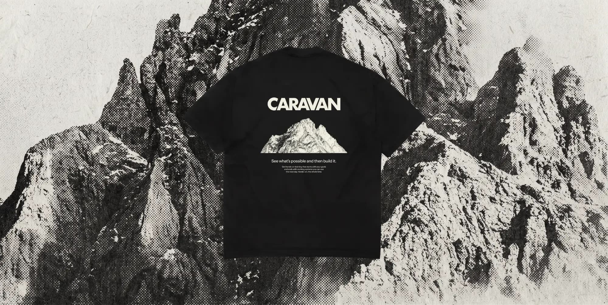 The back of a black Caravan tee over a black and white halftone of jagged mountain peaks: the wordmark, a mountain illustration and See what's possible and then build it.