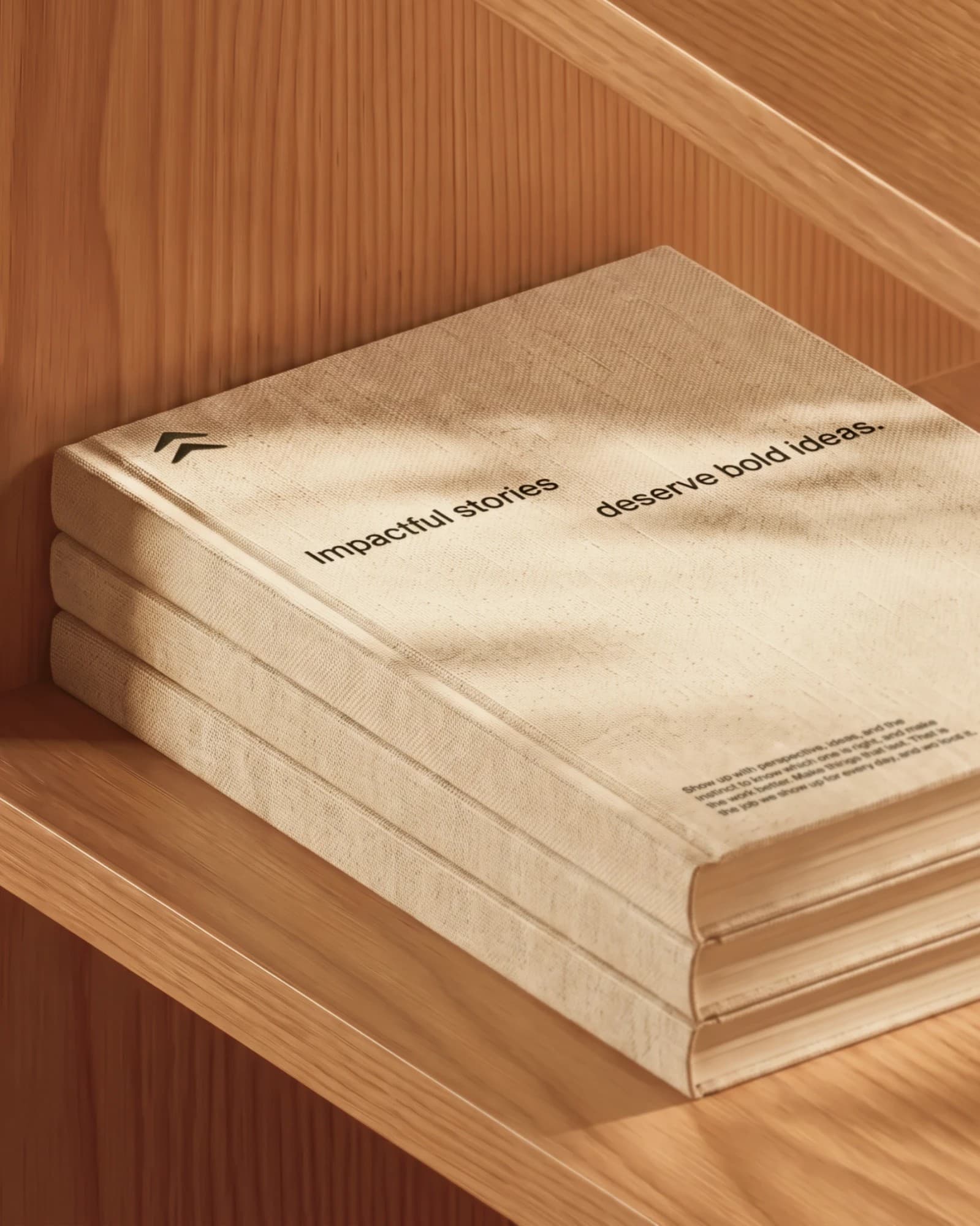 Three linen-bound Cedar brand books stacked on a wooden shelf, the cover reading Impactful stories deserve bold ideas